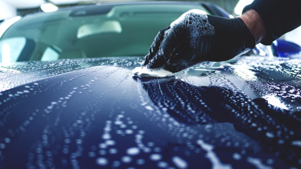 Using a clay bar to remove contaminants from a car's paint in Birmingham, enhancing smoothness and protection.